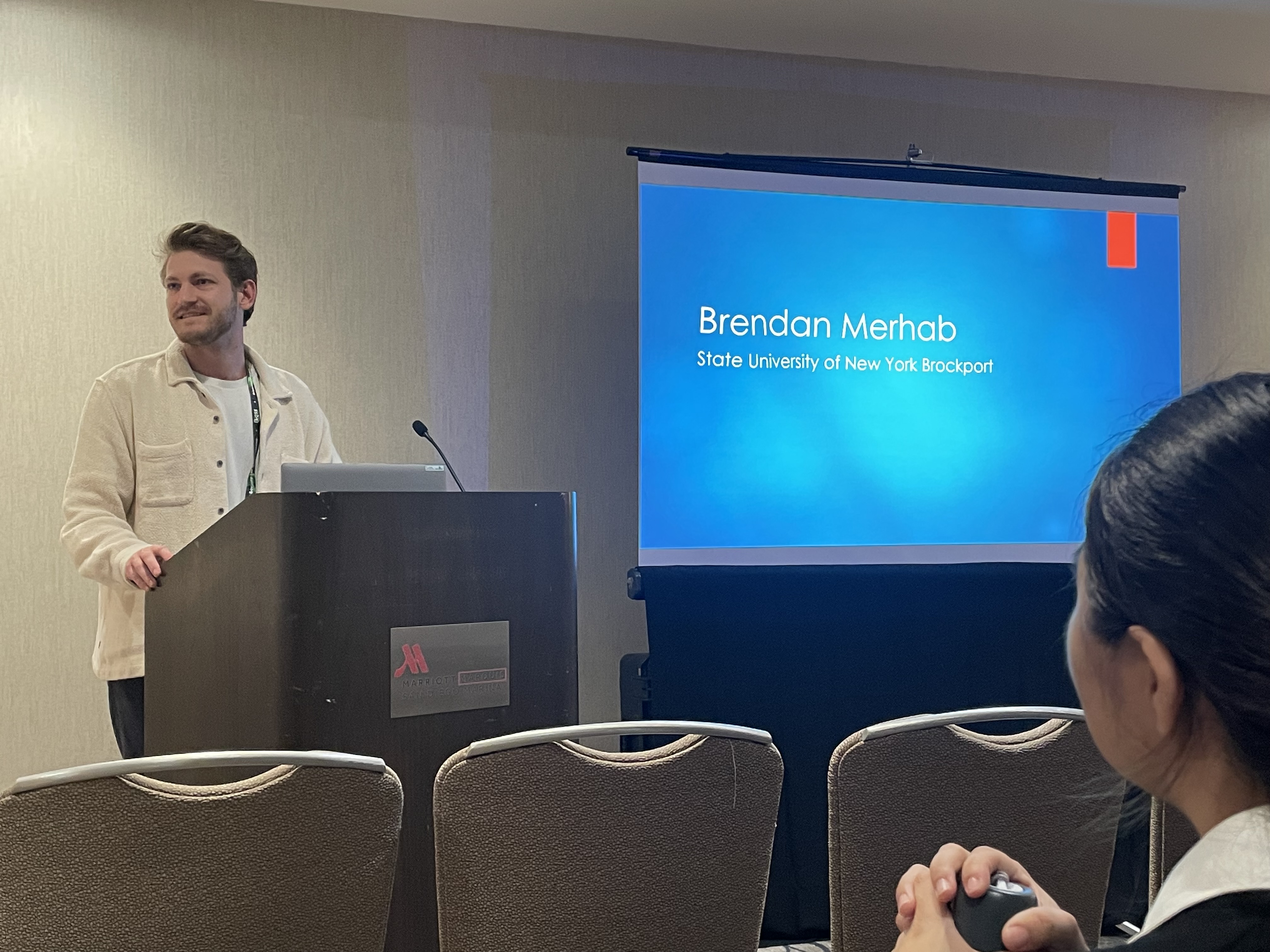Brendan Merhab presenting his research at a conference podium